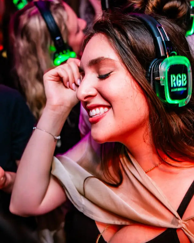 Vrouw met groen oplichtende koptelefoon danst met gesloten ogen
