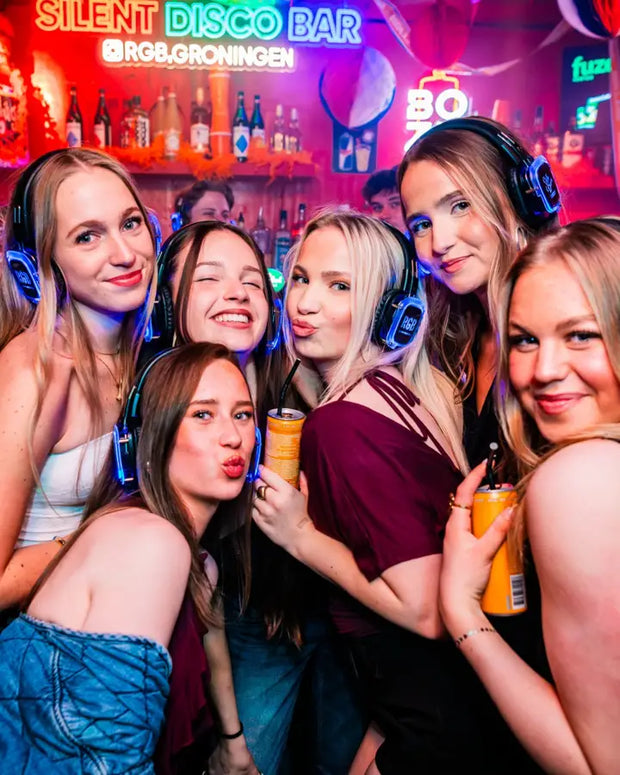 Groep vriendinnen met koptelefoons poseert onder neonletters